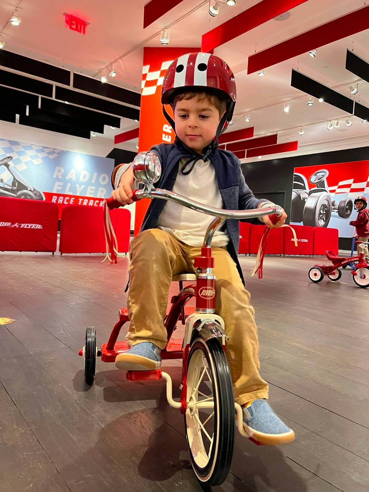 A young boy rides a tricycle inside the Radio Flyer store. 