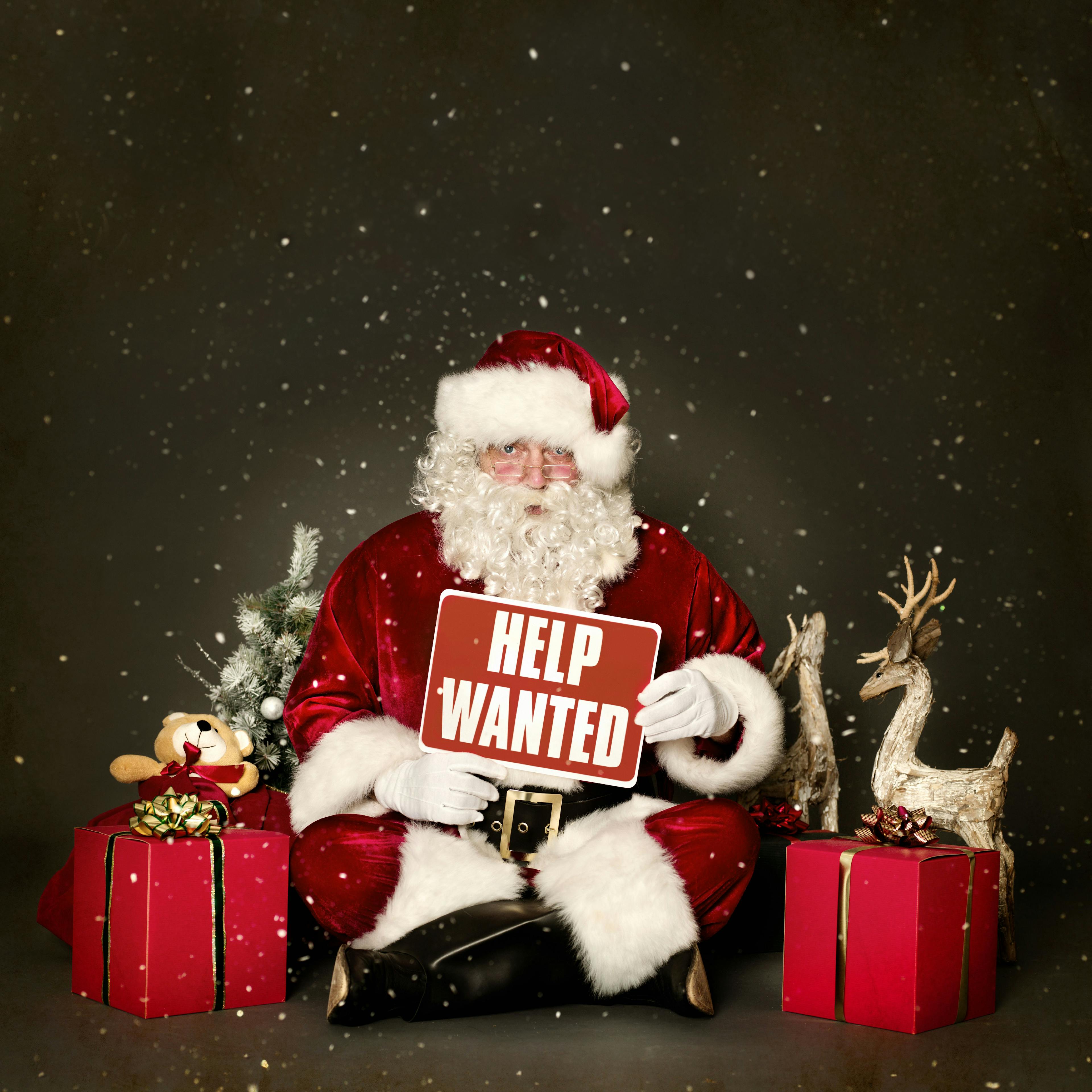 A Santa Claus holding a “help wanted” sign.